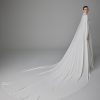 Pronovias Alexandrine trouwjurk met elegante cape, laag uitgesneden rug, en vloeiende crêpe stof.