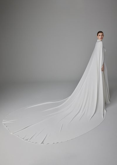 Pronovias Alexandrine trouwjurk met elegante cape, laag uitgesneden rug, en vloeiende crêpe stof.