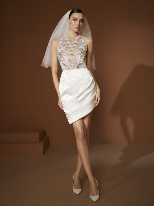 De Elisabetta Franchi X Pronovias Evelyin trouwjurk met hoge rokzoom en geborduurde top.