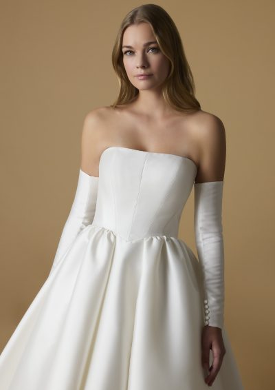 Close-up van de strapless bodice van de Mephis trouwjurk met elegante, lange mouwen.