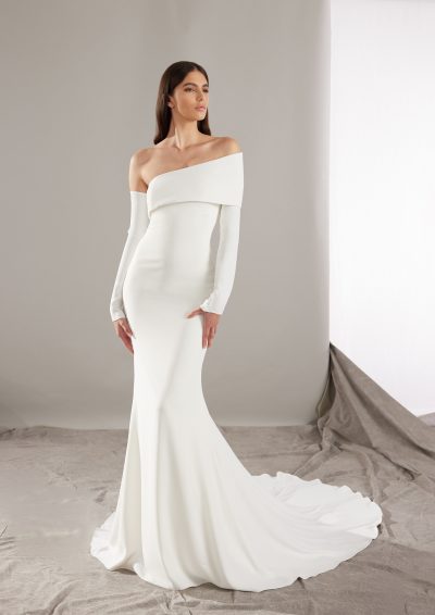 Pronovias Rusty trouwjurk met asymmetrische schouder en lange mouwen, fit-and-flare stijl.