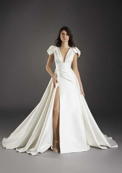 Volledig beeld van de Atelier Pronovias Vella-jurk, toont de elegante A-lijn met hoge split.