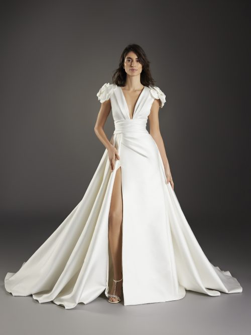 Volledig beeld van de Atelier Pronovias Vella-jurk, toont de elegante A-lijn met hoge split.